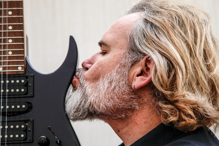 A Long Haired Blonde Bearded Man Kissing Hir Electric Guitar