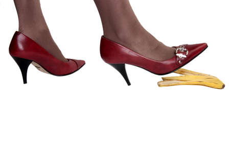 Feet in red pumps on banana peel ageinst a white backgroundの写真素材