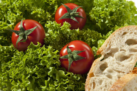 Three tomatoes are in a lettuce with two pices of breadの写真素材