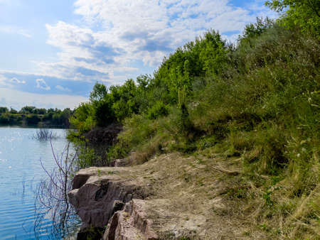 Beautiful cloudy landscape of the banks of a quiet river in summer. Green colorful landscape when the sun went down. Beautiful landscapes of wild nature with a lake with high banks of stone.の写真素材