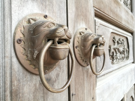 Chinese style door knob with lion head knocker at a Buddhism pagoda in Asiaの写真素材