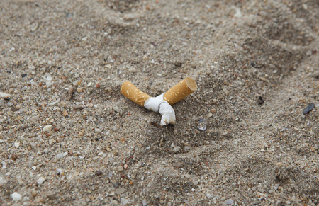 Cigarette butts in the sand on beach.の写真素材