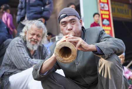 Bac Ha, Vietnam - Oct 17, 2015: Vietnamese civilian artist performing traditional melody with a wooden trumpet at a weekly flea market. Bac Ha along with Sapa are well known favorite destination.のeditorial素材