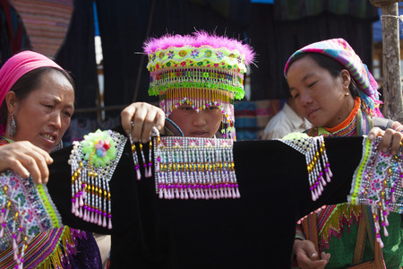 Lao Cai, Vietnam - Oct 17, 2015: Vietnamese Hmong minority girl trying new traditional costume and a colorful traditional hat at a weekly flea market in Bac Ha town.のeditorial素材