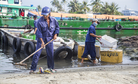 Phu Quoc, Vietnam - Mar 22, 2017: Local cleaners cleaning and carrying garbage on the beach shore of Phu Quoc island, Kien Giang province, south Vietnam.のeditorial素材