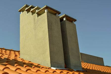 Set of concrete chimneys on a roof under a clear blue sky day