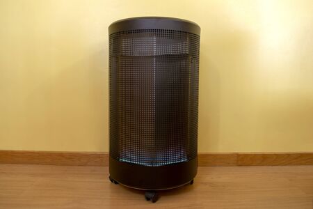 Modern cylindrical gas heater turned on with blue flames inside a dwelling on a cold winter day