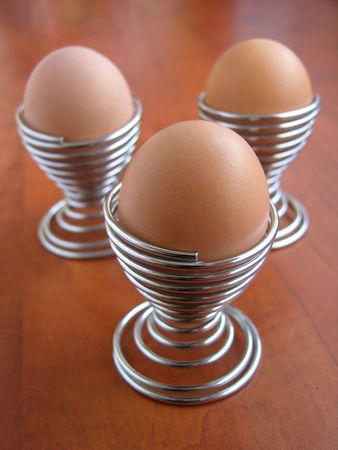 three metal spiral eggcup and three eggsの写真素材