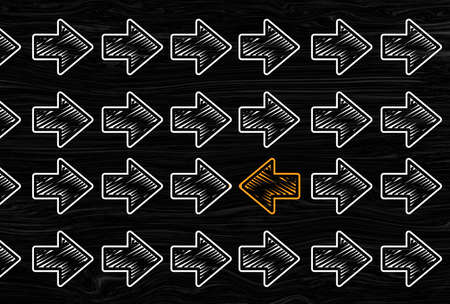 Orange arrows in opposite direction against white others arrows. Opposition, resistance, difference individuality concept. grey chalk background.の写真素材