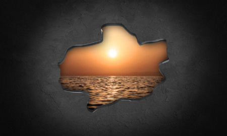 Silhouette of broken hole in concrete wall with sea and sunsetの写真素材