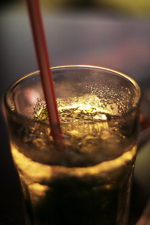 A glass of cold drink with ice and a strawの写真素材
