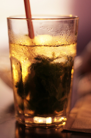 A glass of cold drink with ice and a strawの写真素材