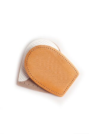 Orthopedic leather heel pad from corns for the correction of different lengths of legs isolated on white background. Leather insert for the forefoot. Medical insoles. Flat Feet Correction.の写真素材