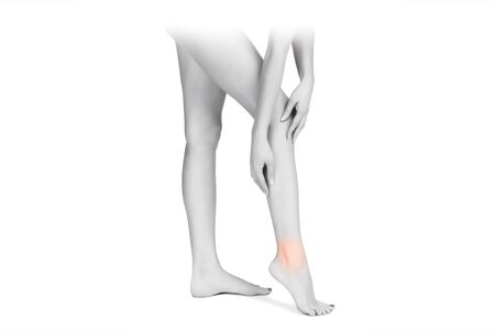 Ankle pain, painful point isolated on white background. Woman with ankle pain holding her aching leg - body pain concept. Joint painの写真素材