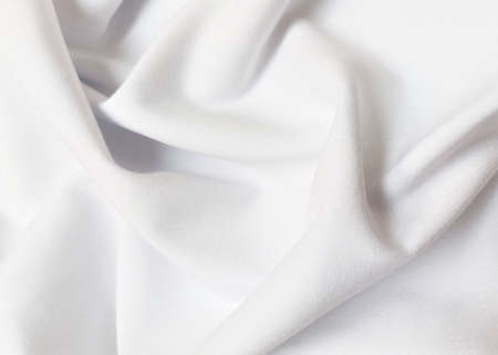 White crumpled or wavy fabric texture background. Abstract linen cloth soft waves. Creases of satin, silk, and cotton. Smooth elegant silk or atlas luxury cloth texture. Bedding Sheets or blanket.の写真素材