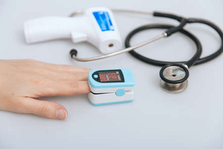 Stethoscope, pulse oximeter and thermometer gun on white background. Phonendoscope. Infrared isometric thermometer gun to check body temperature for virus symptoms. Treatment of cold or flu.の写真素材