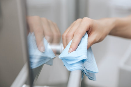 Cleaning glass door handles with an antiseptic wet wipe. Sanitize surfaces prevention in hospital and public spacesの写真素材
