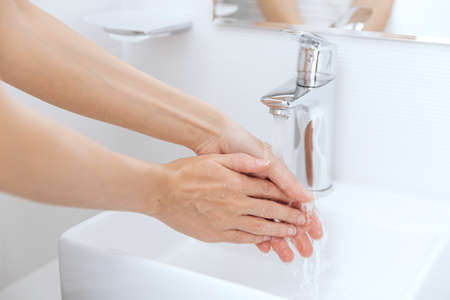 Washing hands under the flowing water tap. Hygiene concept hand detail. Washing hands rubbing with...