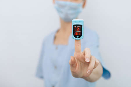 Pulse oximeter with hand of doctor isolated on white. Measuring oxygen saturation, pulse rate and oxygen levels. The concept of portable digital device to measure persons oxygen saturation.の写真素材