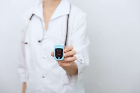 Pulse oximeter with hand of doctor isolated on white. Measuring oxygen saturation, pulse rate and oxygen levels. The concept of portable digital device to measure persons oxygen saturation.の写真素材