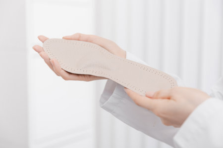 Doctor holding orthopedic insoles in his hands. Orthopedist tests the medical device. Orthopedic insoles on a white. Foot care. Flat Feet Correction. Prevention of flat feet and foot diseases.の写真素材