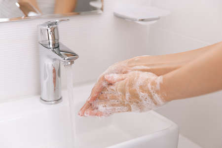 Washing hands under the flowing water tap. Hygiene concept hand detail. Washing hands rubbing with...