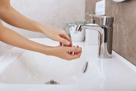 Washing hands under the flowing water tap. Hygiene concept hand detail. Washing hands rubbing with soapの写真素材