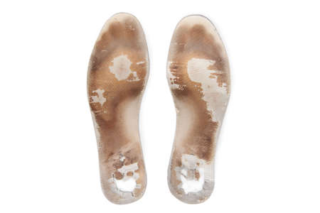 Two old, shabby orthopedic insoles isolated on white background. Dirty leather insoles. Worn out things with holes. Inner soles of shoes. Top view banner close up.の写真素材