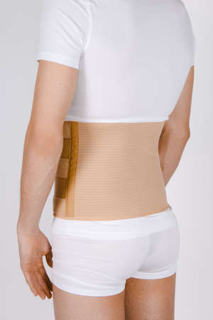 Orthopedic lumbar corset on the human body. Back brace, waist support belt for back. Posture Corrector For Back Clavicle Spine. Post-operative Hernia Pregnant and Postnatal Lumbar brace after surgery.の写真素材