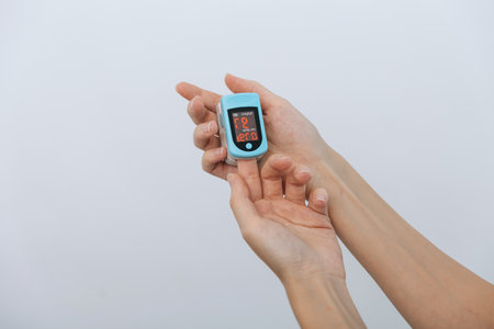 Pulse oximeter with hand of doctor isolated on white. Measuring oxygen saturation, pulse rate and oxygen levels. The concept of portable digital device to measure persons oxygen saturation.の写真素材