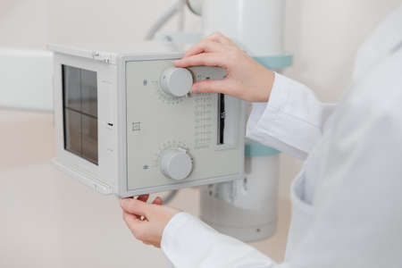 Hospital Radiology Room. Xray machine for fluorography. Doctor radiologist in gown adjusting the X-ray machine for radiography. Medical equipment. Scanning chest, heart or lungs in clinic office.の写真素材