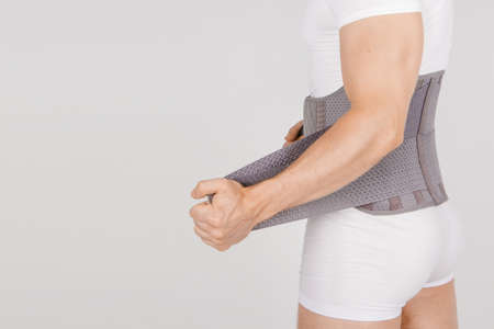 Lumbar brace on the human body isolated on a white background. Trauma of back. Back brace,...