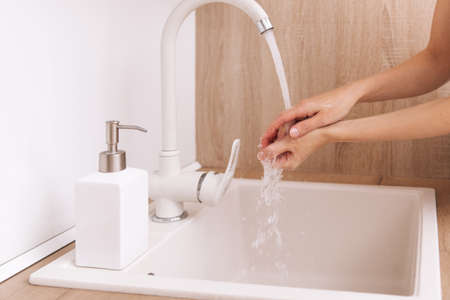 Washing hands under the flowing water tap. Hygiene concept hand detail.の写真素材