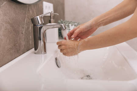 Washing hands under the flowing water tap. Hygiene concept hand detail.の写真素材