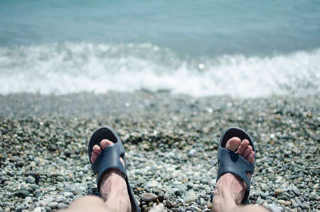 Sky sea and sand. Beautiful seascape, amazing view of pebble coastline. Wave on a pebbly shore. Sea foam. Surf. Beautiful beach. Close-up of the coastline. Traveler feet on the background of the sea.の写真素材