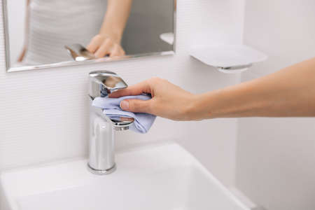 Cleaning the sink faucet with a microfiber cloth. Sanitize surfaces prevention in hospital and public spaces against virus.の写真素材
