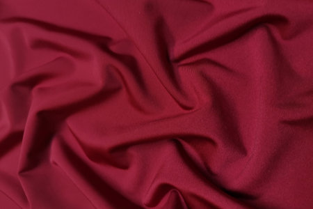 Red supplex crumpled or wavy fabric texture background. Abstract linen cloth soft waves. Silk fabric. Smooth elegant luxury cloth texture. Concept for banner or advertisement.の写真素材