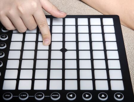 The hand of a child who plays on Launchpad. The MIDI controller that the child controls with his handの写真素材