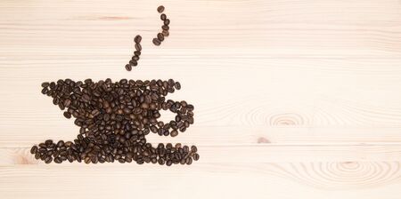 Image of a cup of roasted coffee beans. Steam comes from a cup from a hot drink. Image of a cup of coffee collected on a wooden textured surface of the table.の写真素材