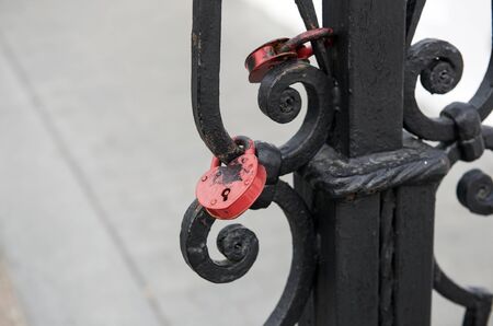Two red padlocks hanging on forged gates painted in black paintの写真素材