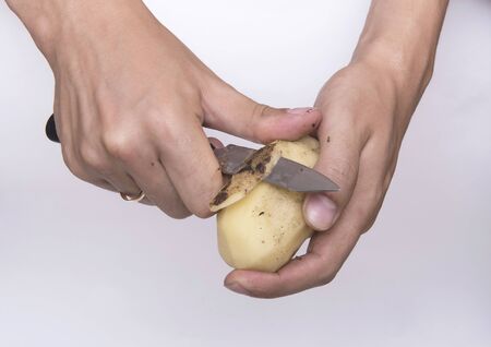 Peel potatoes. Hands of a fair-skinned man with a knife and potatoes. A man is peeling potatoes.の写真素材