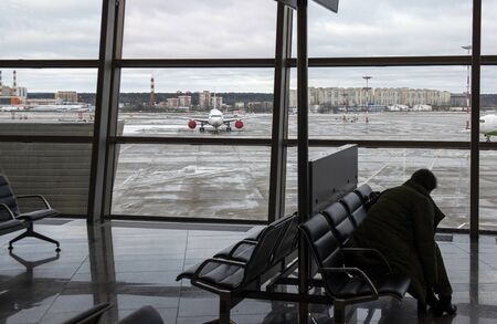Moscow, Russia, 26-01-2020. Waiting room, Vnukovo airport. A woman expects to land on her flight, and there are planes on a snowy airfieldのeditorial素材