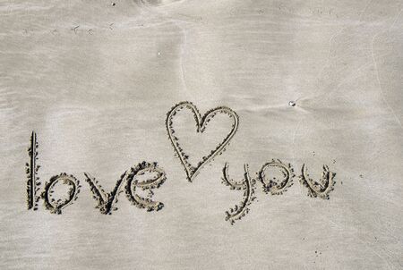 The beach, light dense sand on which the inscription is made in English: I love you. And a heart is drawn. The morning light of the bright sunの写真素材