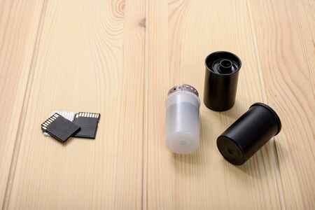 Three flash drives for a digital camera lie on a wooden table opposite three old 35 mm format films. Photographic films are in storage containers の写真素材