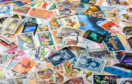 Dolgoprudny, Moscow Region, Russia. 02-24-2020. A collection of postage stamps. A large number of postage stamps on various topics: sports, space, famous people, lie on the surface of the tableのeditorial素材
