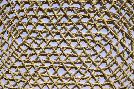 A napkin woven from a thin light thread of bamboo straw that lies on a white sheet of paper. Bright sunshine.の写真素材
