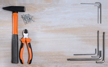 Metal socket wrenches as well as a hammer with screws are laid out on a screw wooden tabletop and...