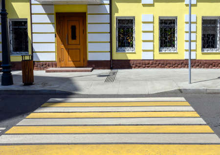 Pedestrian crossing with yellow stripes next to the yellow building in Moscow, Russia.の写真素材