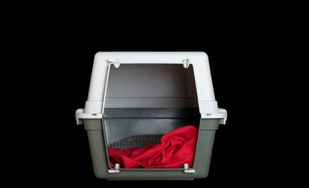 Transportation of pets - a special large plastic container stands on a black background in the studio - isolate, Inside the container lies a red soft blanket.の写真素材