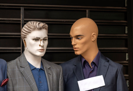 Two male mannequins dressed in suits advertise clothes in a street market in Belgrade. Warehouse grate in the background.の写真素材